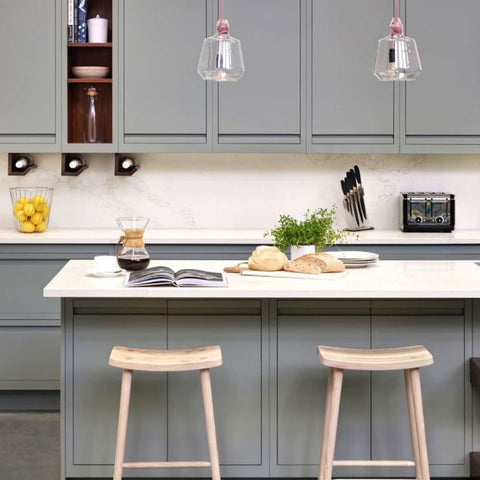Contemporary large clear glass knot pendant lights hanging above a modern kitchen island with grey cabinetry and wooden stools