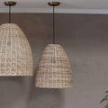 Nkuku Noko Wicker medium conical pendant light with hand-woven natural wicker shade hanging against a textured gray wall
