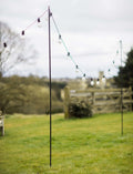 Steel festoon poles for outdoor lighting with bull horn design and pointed base in garden setting