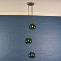 Soho small teal glass shade cluster pendant light with three hand-blown globes and adjustable cords against blue brick wall