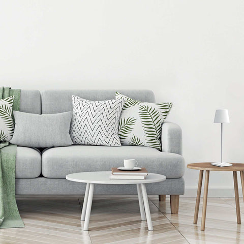 Zafferano Poldina Pro rechargeable white table lamp on wooden side table next to gray sofa with patterned pillows in modern living room