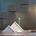 Zafferano Pina Pro rechargeable white table lamp with modern minimalist design on wooden surface next to decorative geometric objects and book