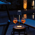 Zafferano Poldina Micro rechargeable sand table lamp illuminating outdoor table with two orange drinks at night