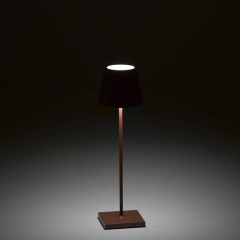Zafferano Poldina Pro rechargeable rust-colored portable table lamp glowing in dark background