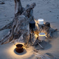 Zafferano Push-up rechargeable table lamps in black and white with warm glow on sand near driftwood