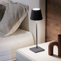 Zafferano Poldina Pro rechargeable black table lamp on bedside table next to bed with modern decor