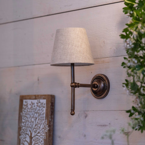 Finberry fabric shade Lupin wall light with bronze fitting and beige lampshade mounted on wooden wall.
