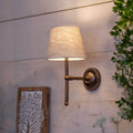 Finberry Fabric Shade Lupin wall light with beige fabric shade and bronze finish mounted on light wooden wall.