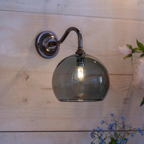 Soho Smoked Glass Wall Light with medium smoked glass globe shade and antique brass finish mounted on wood wall