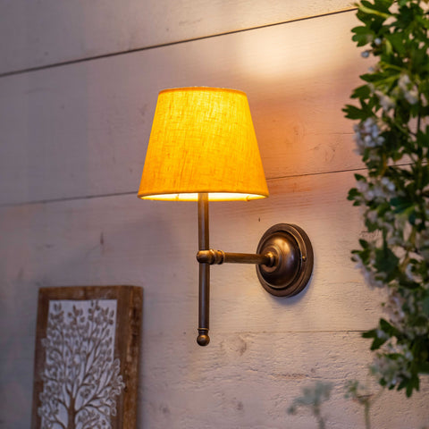 Finberry fabric shade Lupin wall light with yellow shade and bronze fitting mounted on wooden wall.