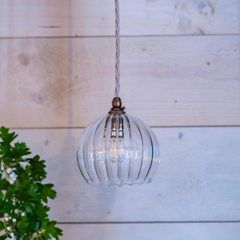 Soho small ribbed glass shade pendant light with hand-blown ribbed glass and twisted cable hanging against wooden wall background