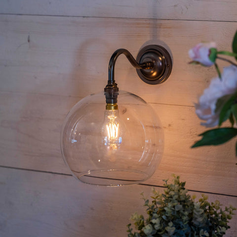 Modern Soho large clear glass shade wall light with antique brass finish mounted on wooden wall
