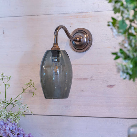Camber small smoked glass shade wall light with bronze fixture on white wooden wall in contemporary interior