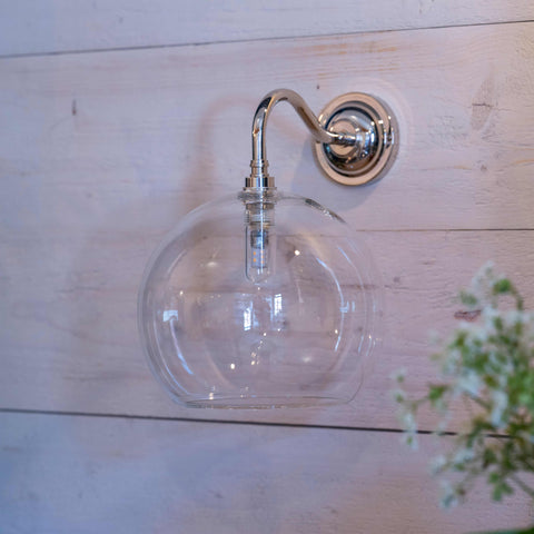 Soho Large Clear Glass Bathroom Wall Light with round clear glass shade and chrome finish mounted on light wood wall