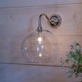 Soho Large Clear Glass bathroom wall light with a chrome finish and spherical clear glass shade mounted on a wooden wall