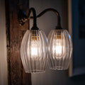 Camber Medium Ribbed Glass Shade Double Arm Wall Light with swan neck arms and warm ambient lighting