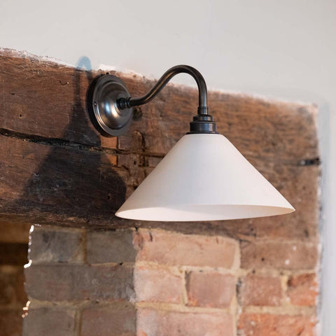Coolie Ceramic Shade Wall Light mounted on a brick fireplace