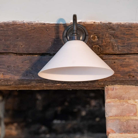 Coolie Ceramic Shade Wall Light mounted on a brick fireplace