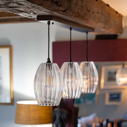 Bespoke bar pendant light with three ribbed camber glass shades hanging over kitchen island