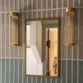 Tall Glass Rodded Bathroom Wall Light in Satin Brass next to a mirror