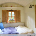 Foxton Adjustable Spotlight by Chehoma mounted on a white wooden wall in a cozy room with natural light and soft bedding