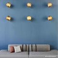 Chulainn Dish Wall Light vintage brass dish wall lamps with walnut arms mounted on blue wall above gray sofa with cushions