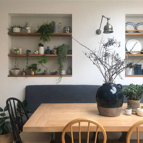 Dale Adjustable Wall Light mounted above dining area with wooden table and decorative plants in a modern cozy room