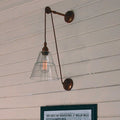 Kairi Pulley Wall Light with adjustable pulley cable and clear glass shade mounted on white wooden wall
