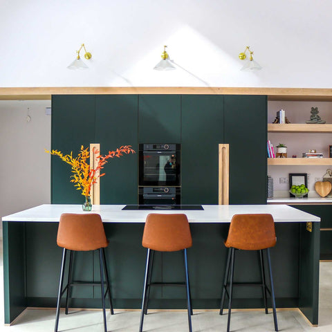 Rebell Prismatic Adjustable Wall Light with prismatic glass shade in antique brass above modern kitchen island with brown stools