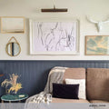 Dublin Picture Light brass wall-mounted adjustable light above framed artwork in stylish living room setting