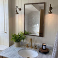 Kent Adjustable Wall Light in brass finish illuminating a bathroom vanity with marble countertop and gold fixtures