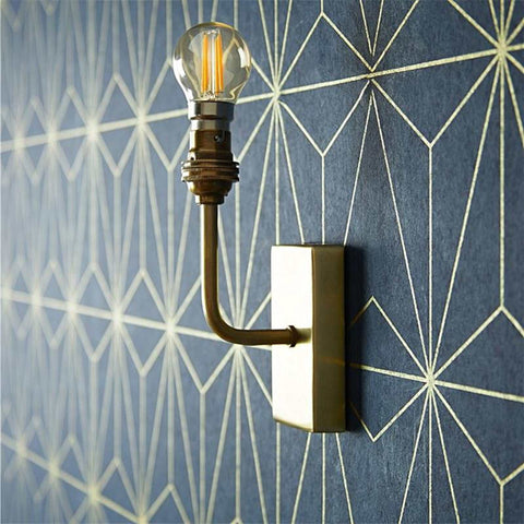 Pooky Melville vintage glass wall light with antique brass finish mounted on geometric patterned wall