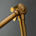 Close-up of adjustable arm joint of brass Pooky Stork Wall Light in antique finish against gray background
