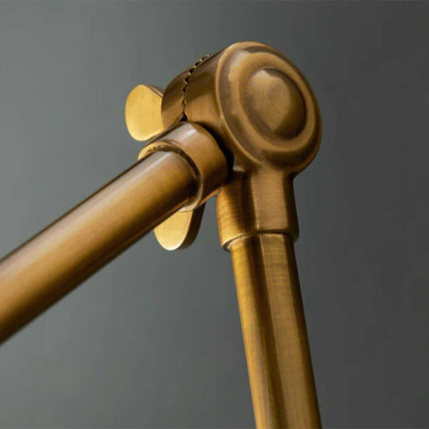Close-up of adjustable arm joint of brass Pooky Stork Wall Light in antique finish against gray background