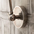 Pooky Stork Wall Light in antique silver finish with adjustable brass arm mounted on wooden wall