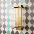Pooky Roddy Wall Light in brass finish with vertical glass rods mounted on geometric tiled wall