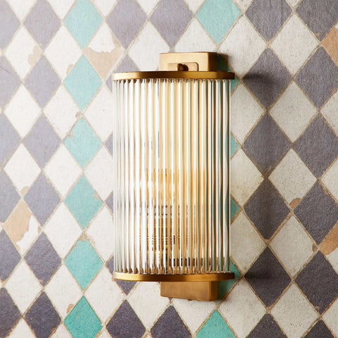 Pooky Roddy Wall Light in brass finish with vertical glass rods mounted on geometric tiled wall