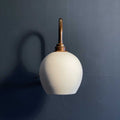 Stanford medium ceramic shade wall light with matte finish and brass mounting on dark wall background