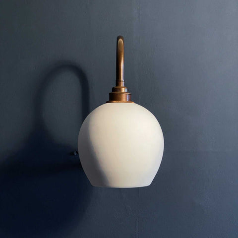 Stanford medium ceramic shade wall light with unglazed matte finish and warm glow on dark wall