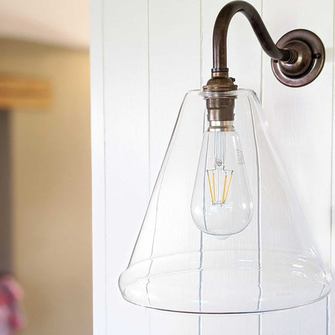 Rye Clear Glass Wall Light with medium handblown glass shade and bronze swan neck bracket mounted on white wall