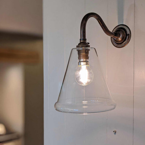Rye small clear glass shade wall light with vintage-style bulb and metal fixture mounted on white wall