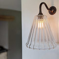 Rye medium ribbed glass shade wall light with warm glow and vintage-style metal arm