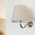 Wall light with natural linen fabric shade and chrome curved arm mounted on white wall