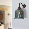 Hythe Small Smoked Glass Shade Wall Light with vintage metal arm and exposed filament bulb mounted on white wall in modern interior