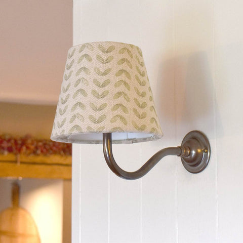 Green Sycamore Linen fabric shade wall light with metal arm mounted on white wall, providing soft ambient lighting