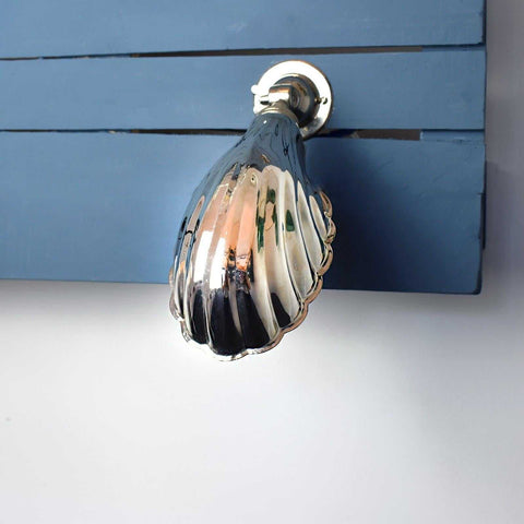 Hadlow Adjustable Brass Shell Wall Light with vintage shell design mounted on blue wooden panel