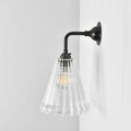 Rye Ribbed Glass small wall light with clear ribbed glass shade and dark metal arm for warm ambient lighting
