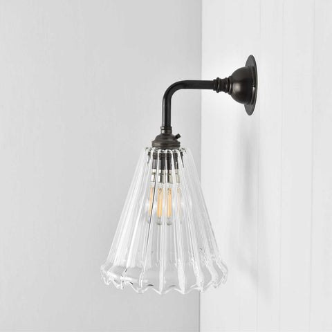 Rye Ribbed Glass small wall light with clear ribbed glass shade and dark metal arm for warm ambient lighting