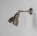 Moorlea brass wall light in aged brass finish with adjustable arm mounted on a white wall