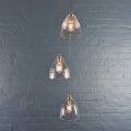 Margate Small Ribbed glass shade cluster pendant light with three ribbed clear glass shades against a gray brick wall background